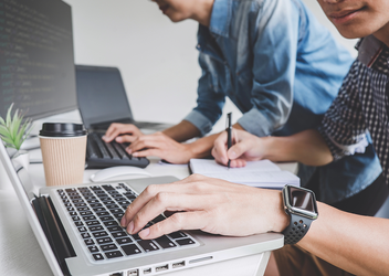 An image of two men writing software on laptops